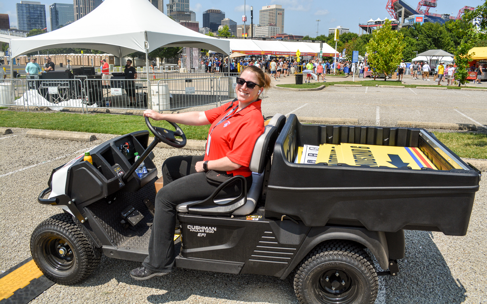 Kristen Moser (manager, event operations) driving wayfinding signage around in a utility cart